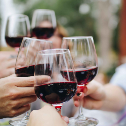 Cinq personnes trinquent avec leurs verres de vin rouge.
